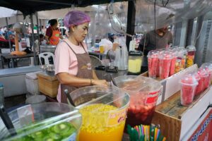 A vendor preparing fresh fruit juices at a market stall
